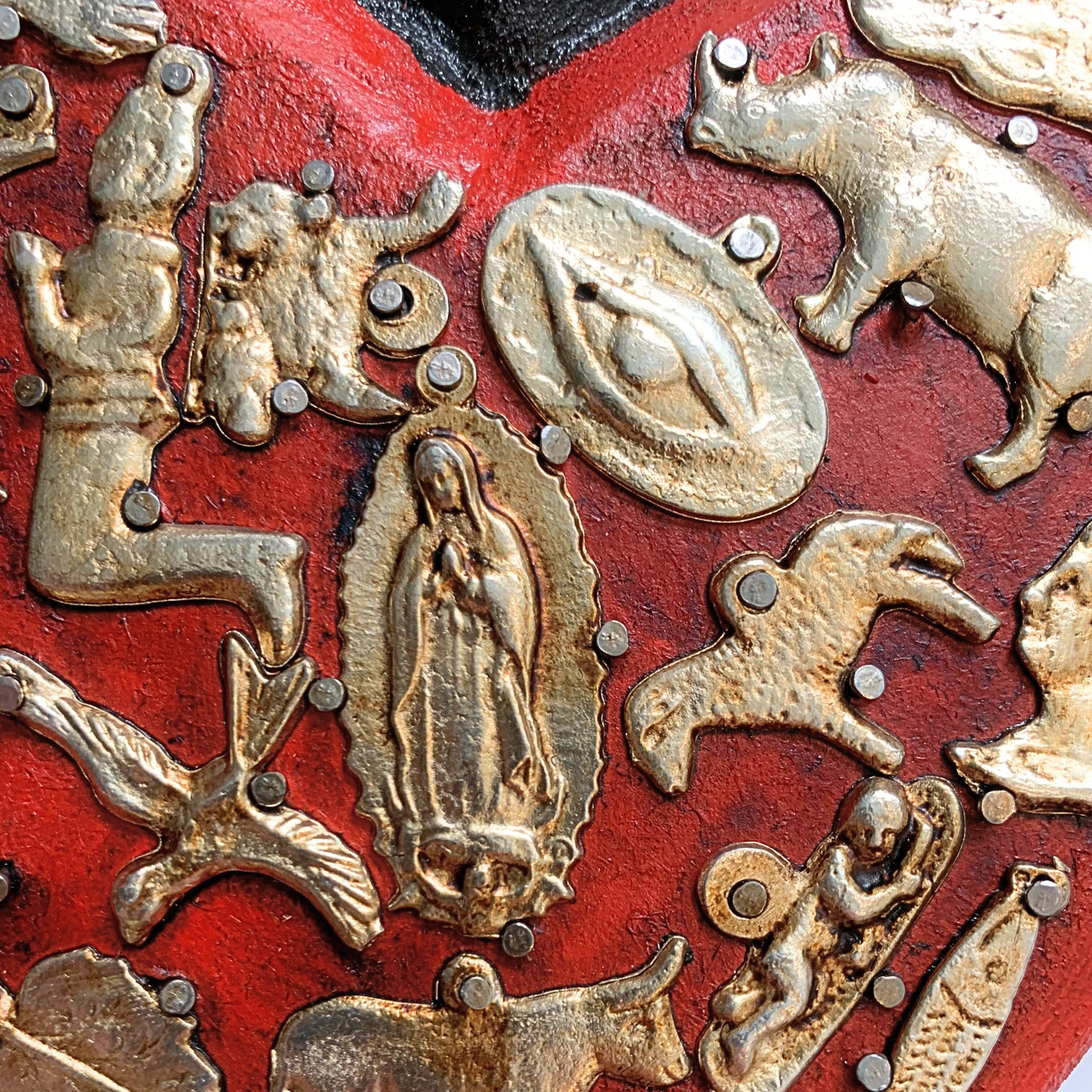 close up of Ex Voto Wooden Sacred Heart with Milagros, handcrafted and hand-painted by Mexican artisans, brightens up any room with its vibrant colors.