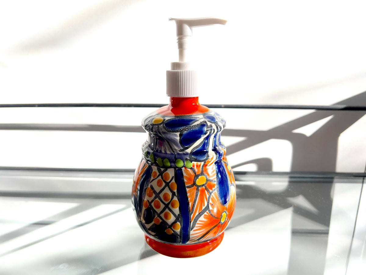 Multicolor bell soap dispenser on a glass shelf