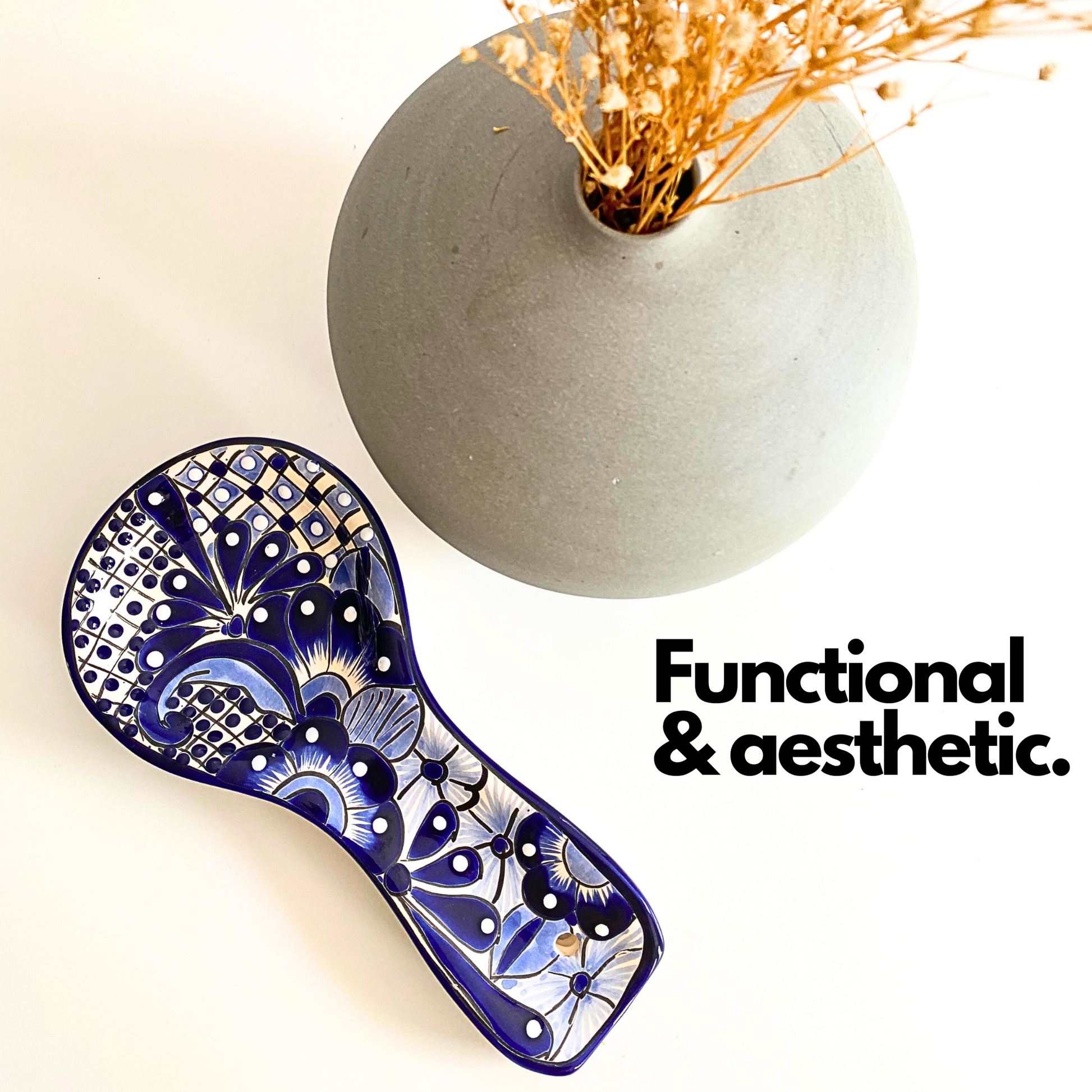 Blue and white Talavera-style ceramic spoon rest, hand-painted in Mexico — flat lay beside a stone vase with dried flowers
