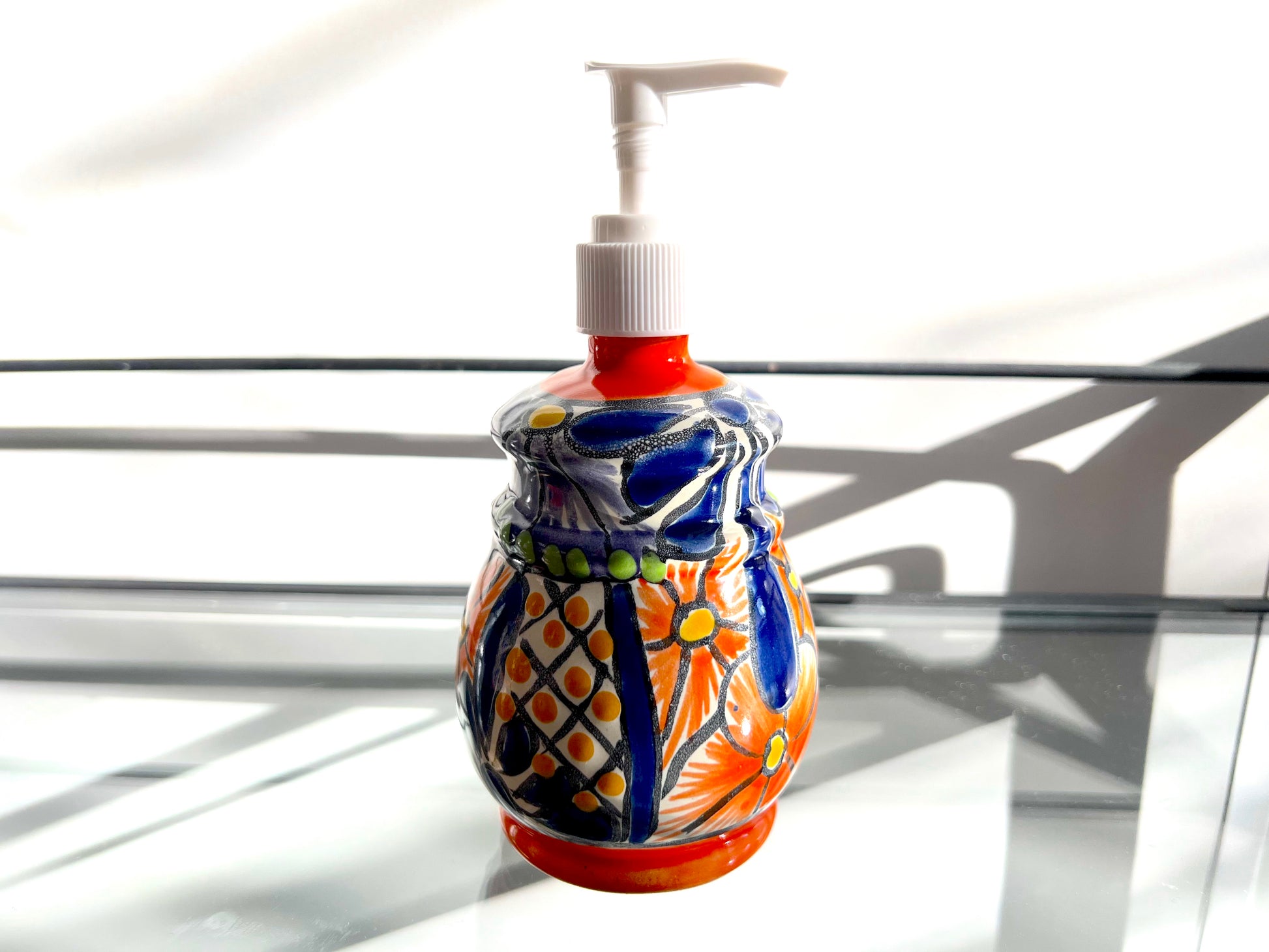 A multicolored, bell design, hand-painted Talavera ceramic soap dispenser sourced from skilled Mexican artisans. lifestyle photo