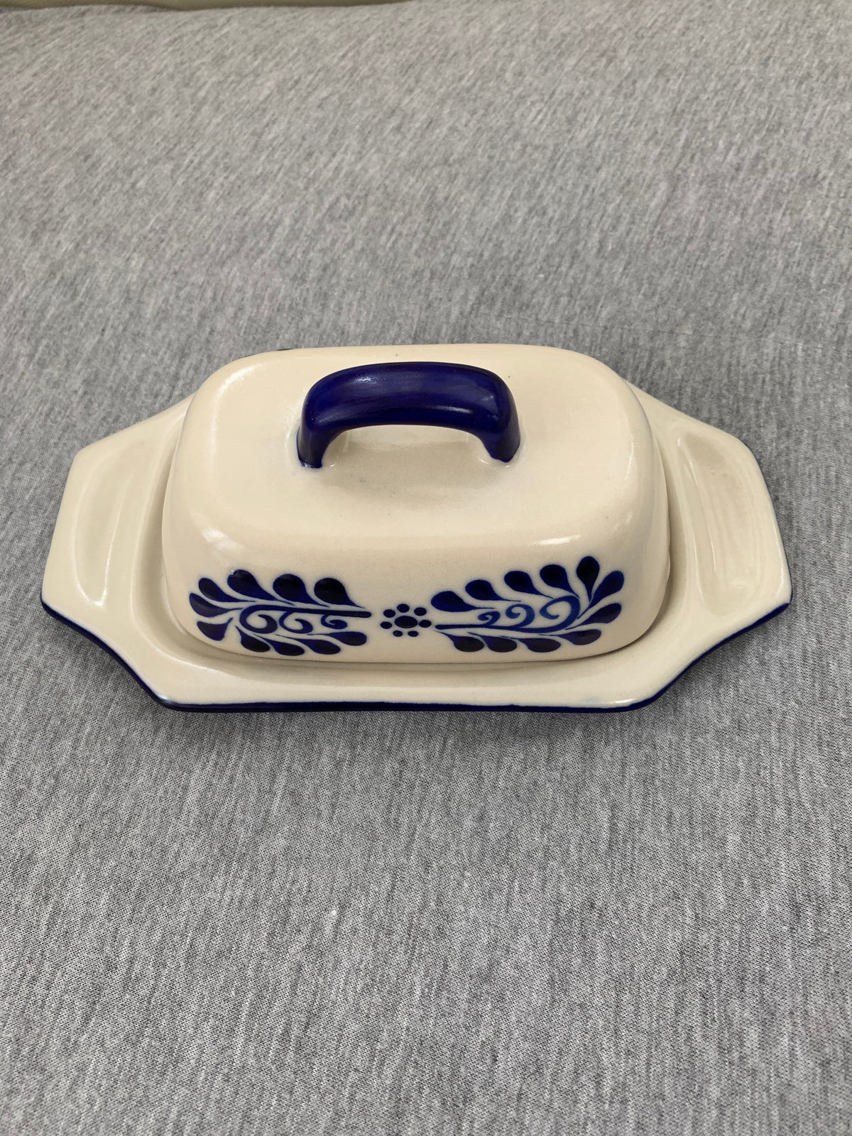 White ceramic butter dish with blue hand-painted details on a gray surface